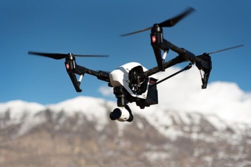 A white, flying drone. Photo by Mitch Nielsen on Unsplash.